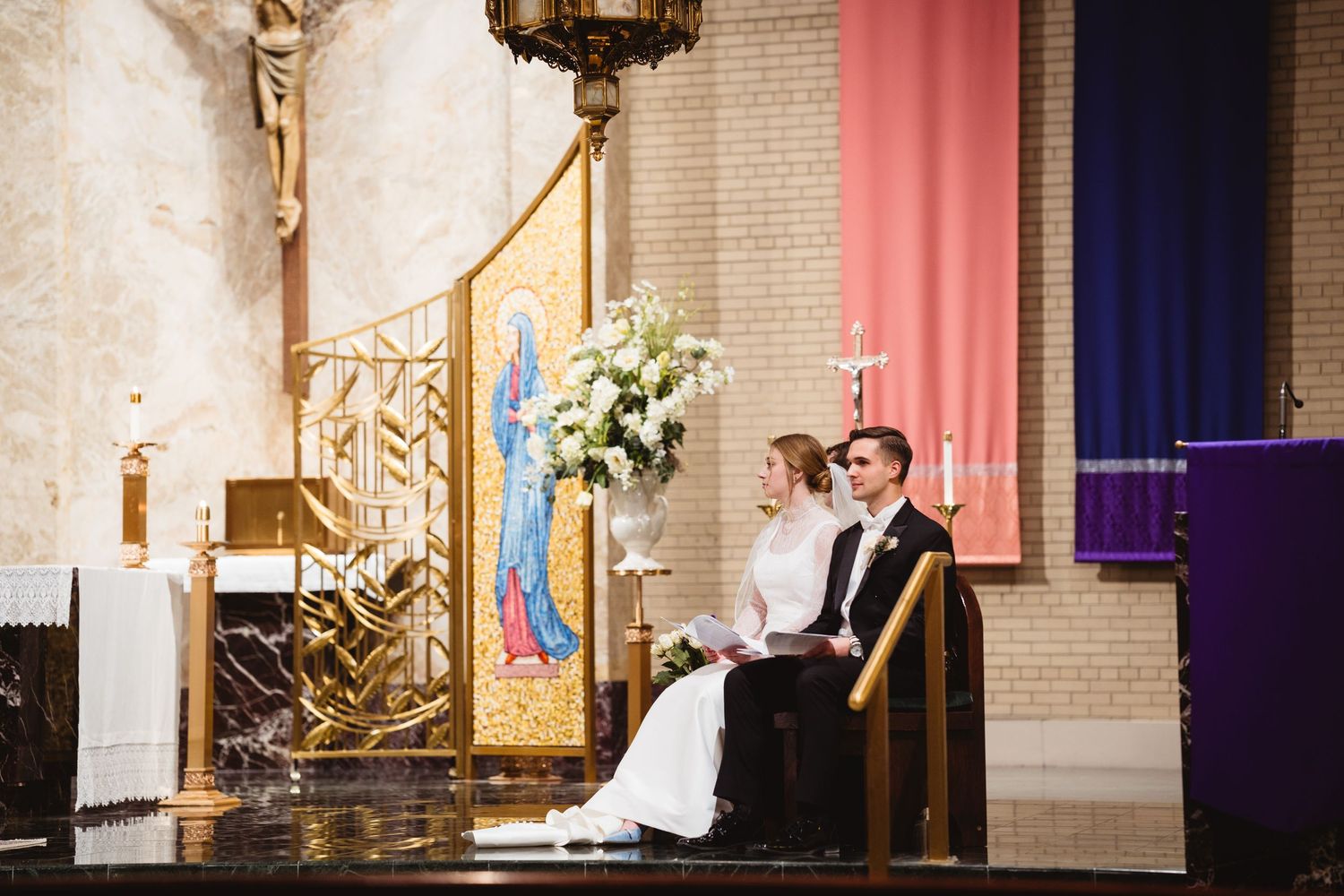 A couple exchanges vows during a traditional church wedding ceremony with ornate architecture and floral decorations.