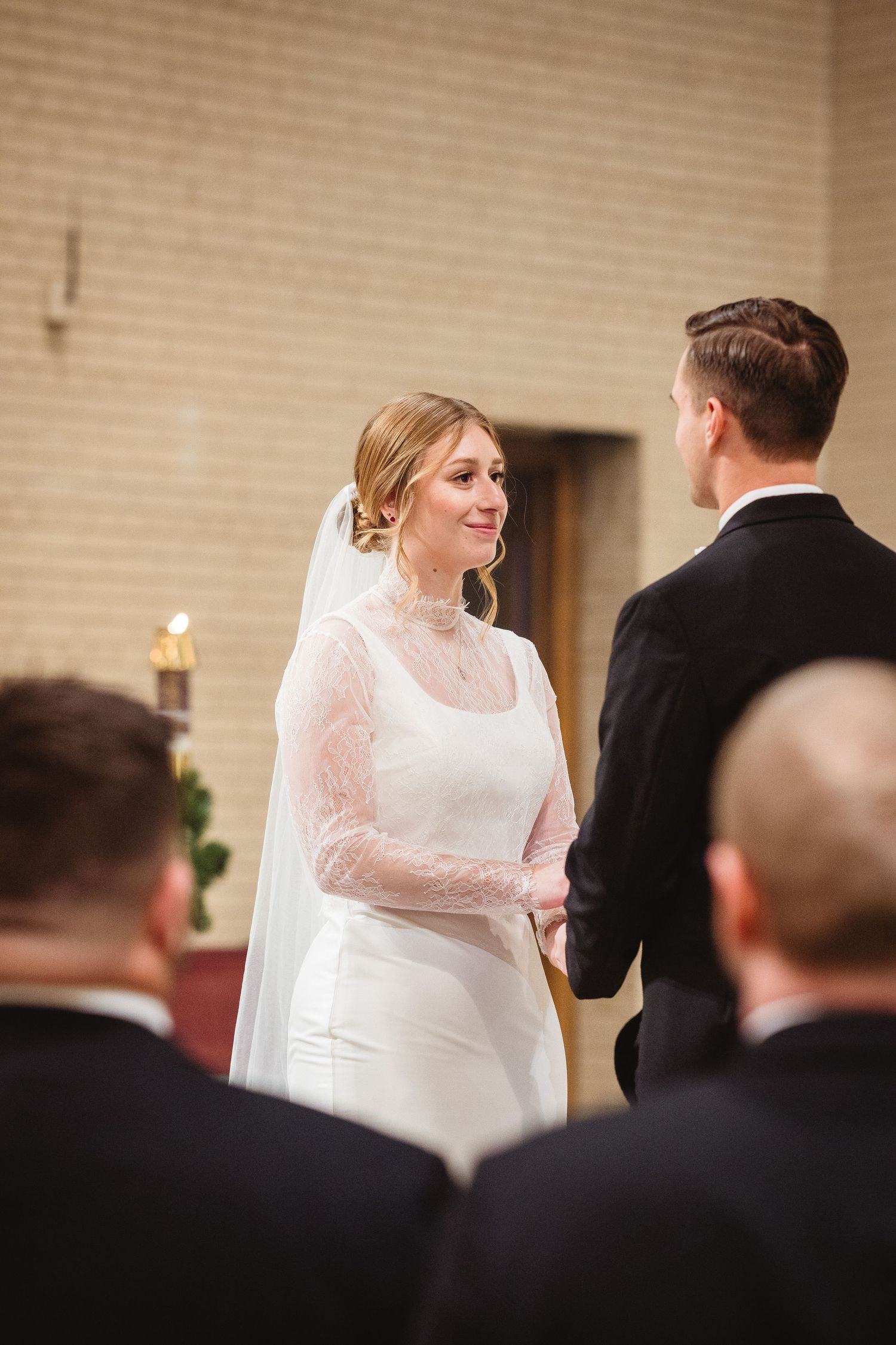 A couple shares their first dance at their wedding reception with the bride wearing a white lace dress.