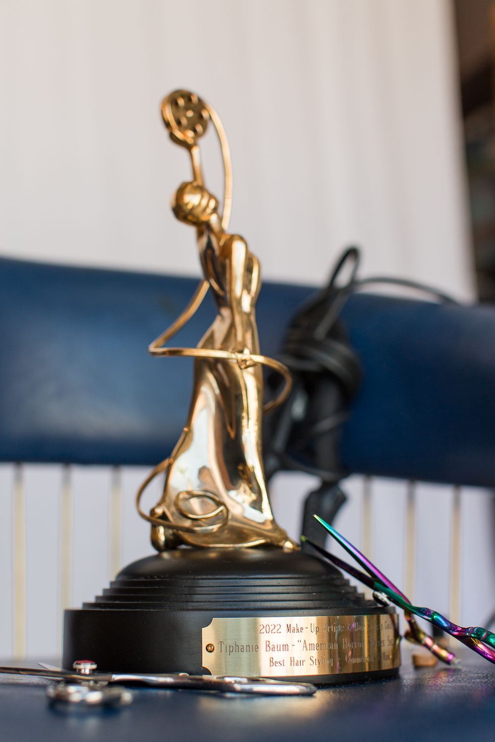 Golden trophy statue depicting a figure in motion displayed on dark blue surface.