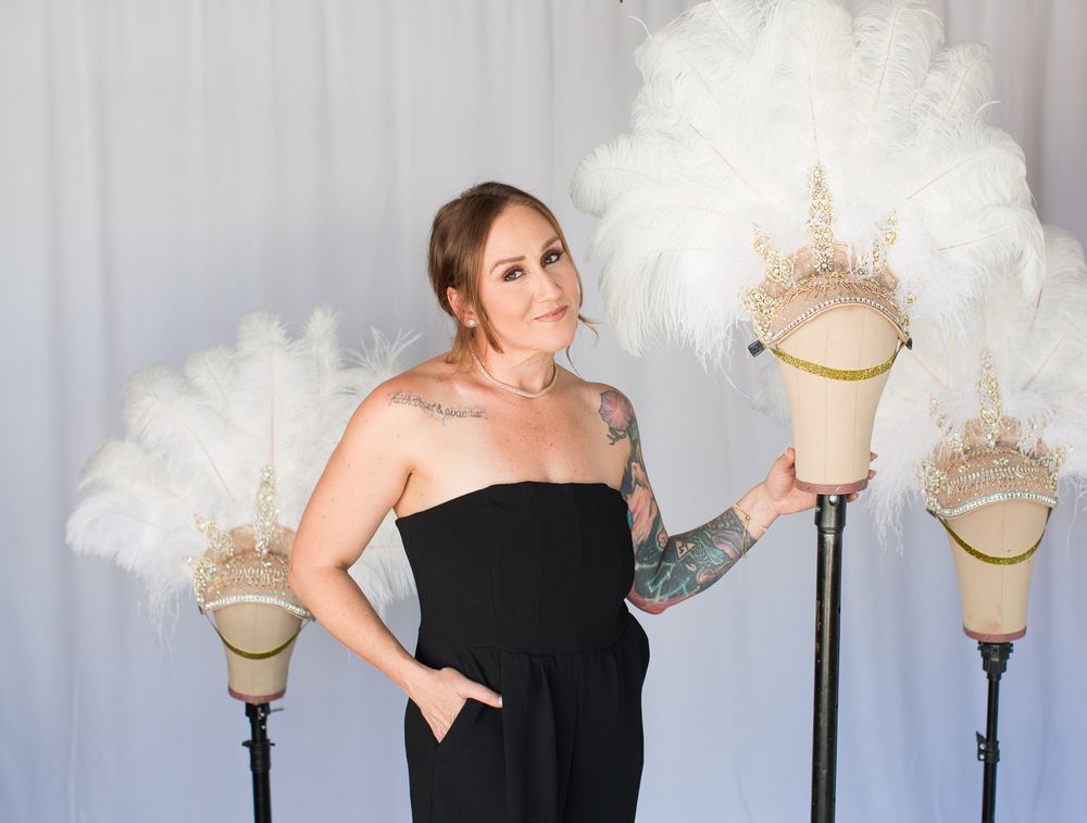 Person in black dress poses near decorative white cloud props against light backdrop.