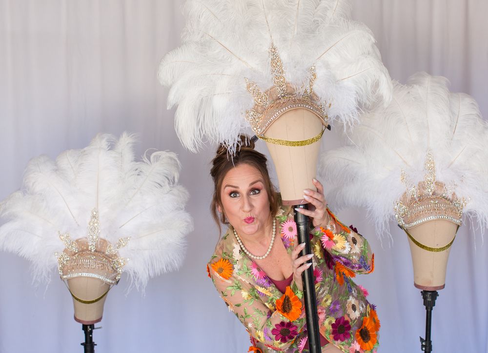 Fashion photoshoot setup with white feather props and mannequin head displays.