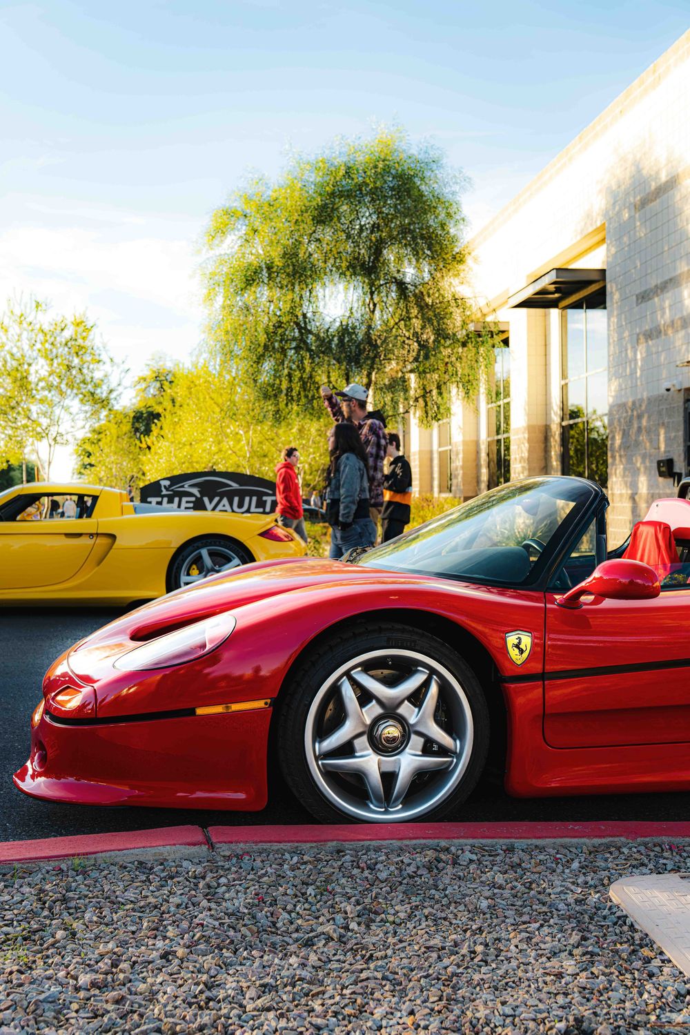 Three views of a sleek red Ferrari sports car parked on gravel showing different angles of its aerodynamic design.