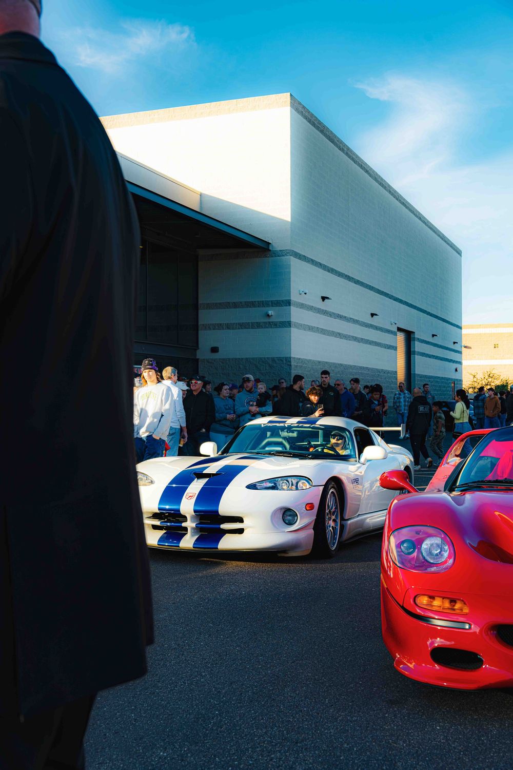 A row of exotic sports cars including white and red models displayed outside a commercial building.