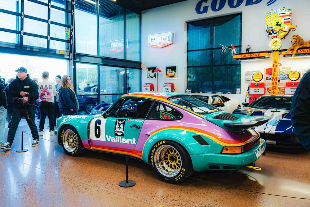 Colorful vintage race cars displayed in a museum showroom with Goodyear signage and reflective floors.