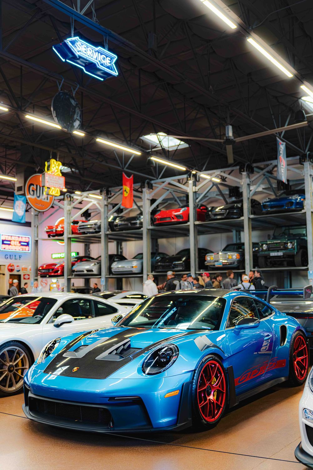 Three bright blue Pagani Huayra supercars displayed in a luxury car showroom with red accents and lighting.