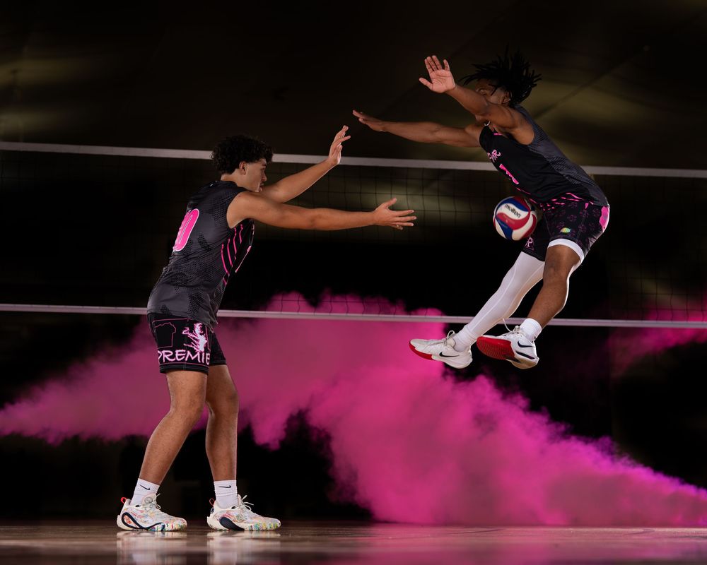 Figure skater performs a graceful jump sequence on ice with pink lighting effects in the background.