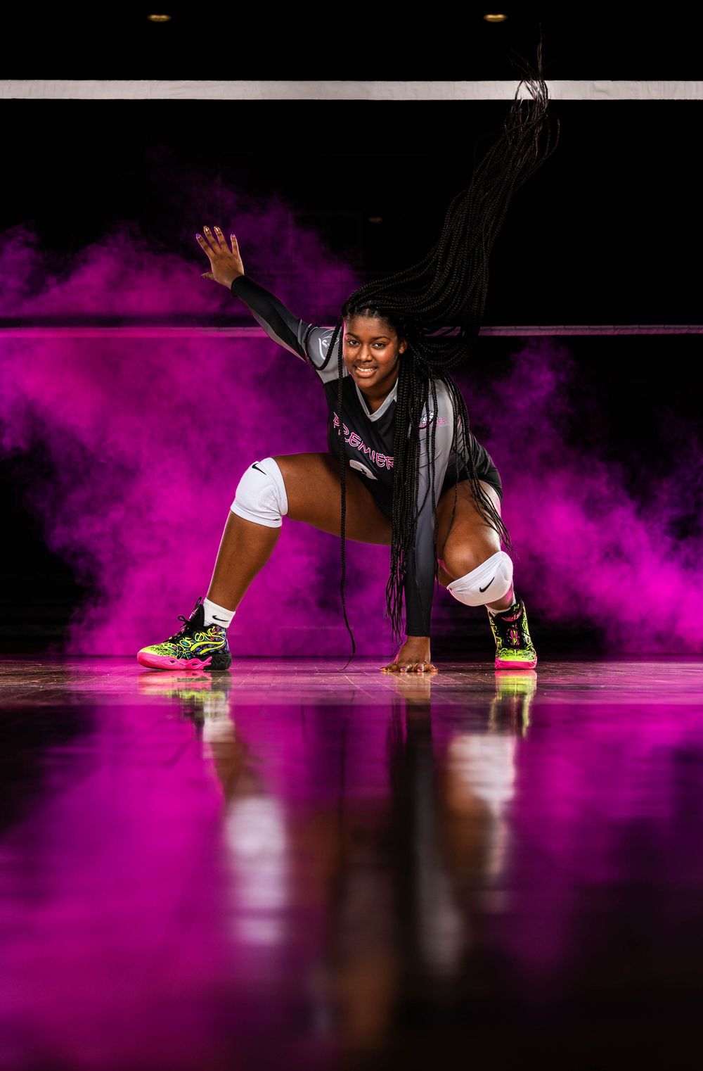 Basketball players' legs are silhouetted against a dramatic pink smoke effect on a dark court during player introductions.