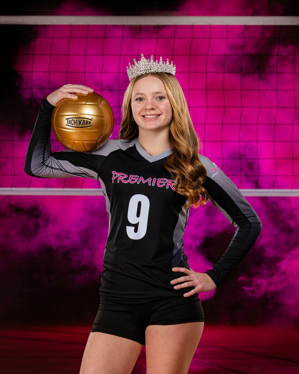 A volleyball player in a black Premier jersey with number 9 poses with a gold volleyball against a pink smoky backdrop.