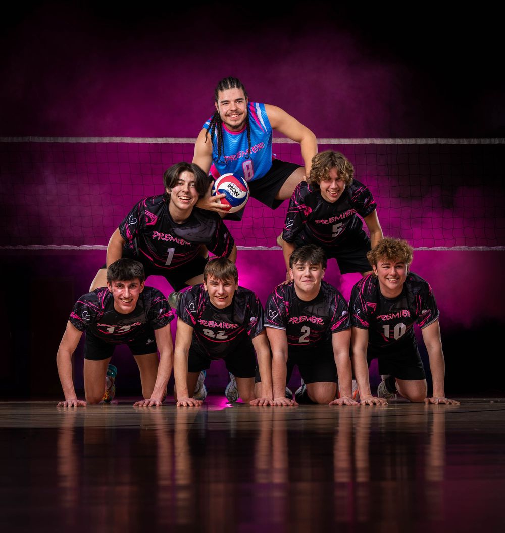 Dancers in black costumes perform a synchronized floor routine on a dark stage with purple lighting effects.