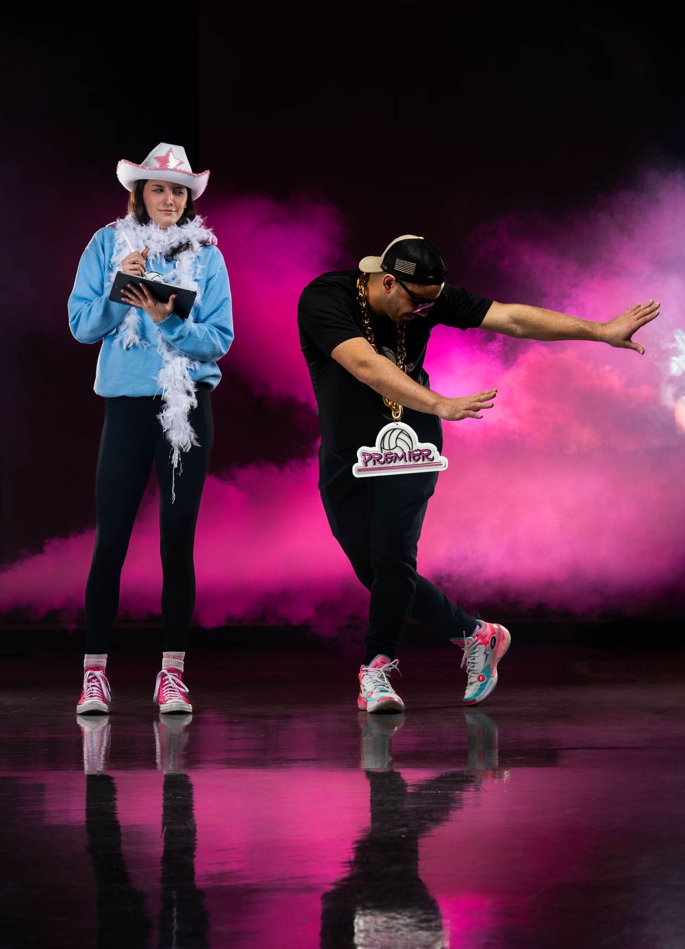 Dancers perform a dynamic sequence with pink smoke effects on a dark stage creating a dramatic atmospheric scene.