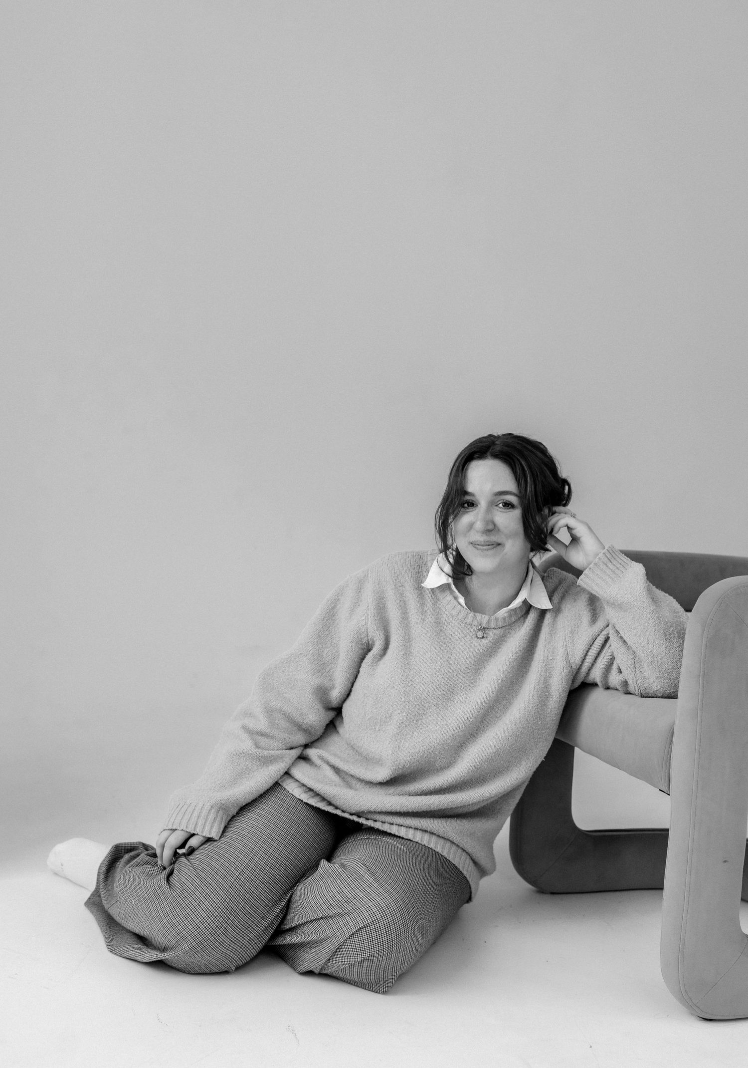Minimalist studio portraits in grey tones showing relaxed poses on couch.