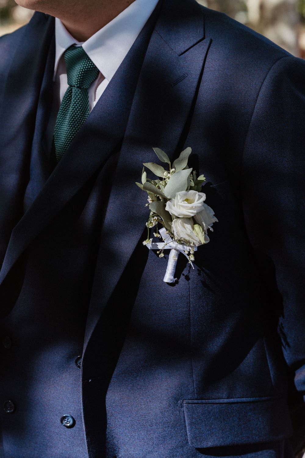 une boutonnière verte et blanc sur un costume bleu