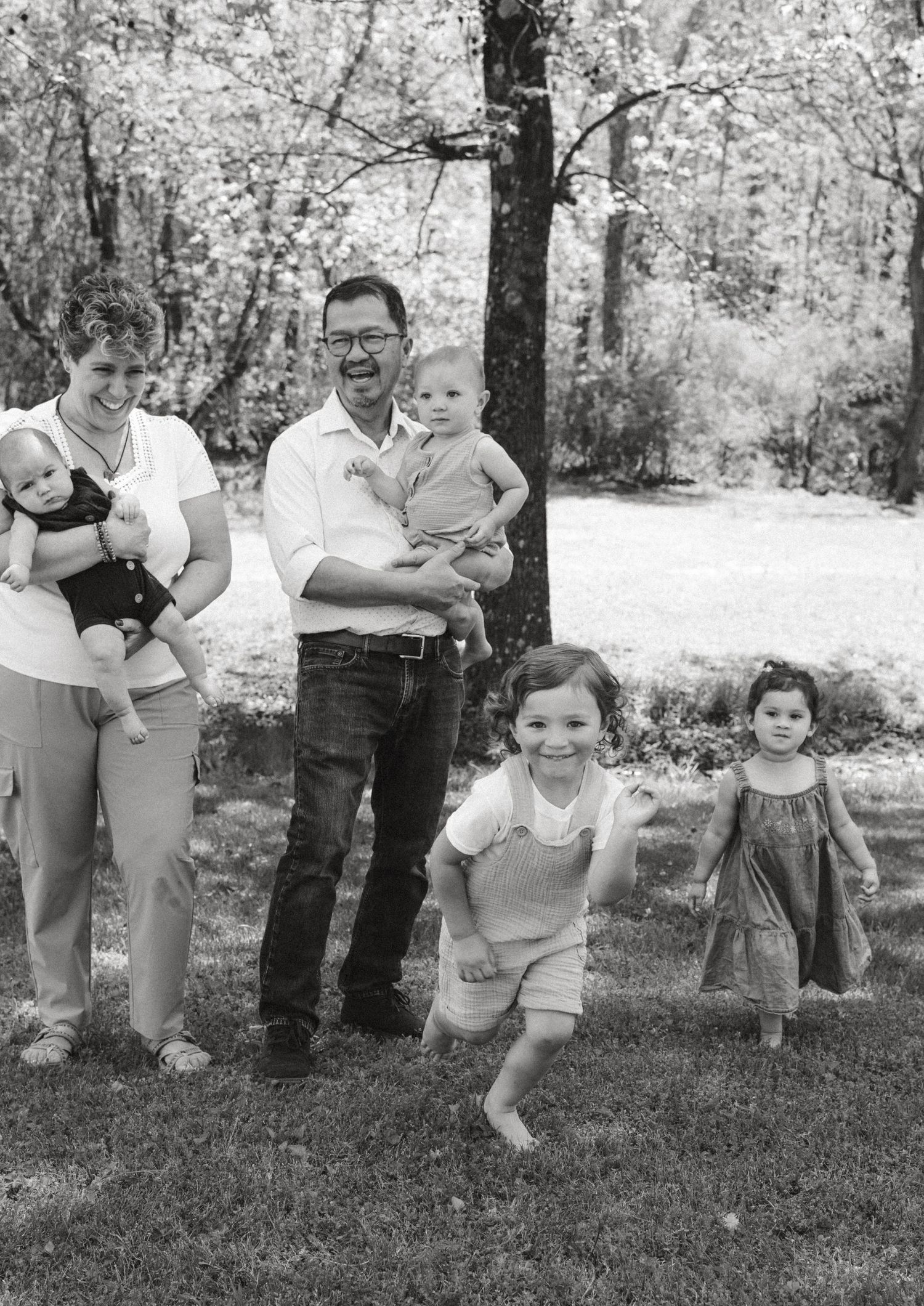 Black and white family portrait session showing playful moments outdoors.