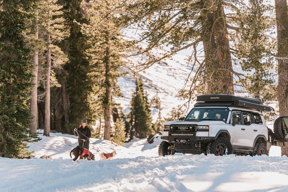 A black Jeep drives through a snowy forest trail during a winter adventure in the mountains.
