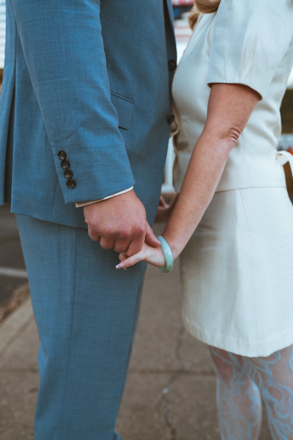 Close-up view of hands holding each other while wearing formal attire in blue and white tones.