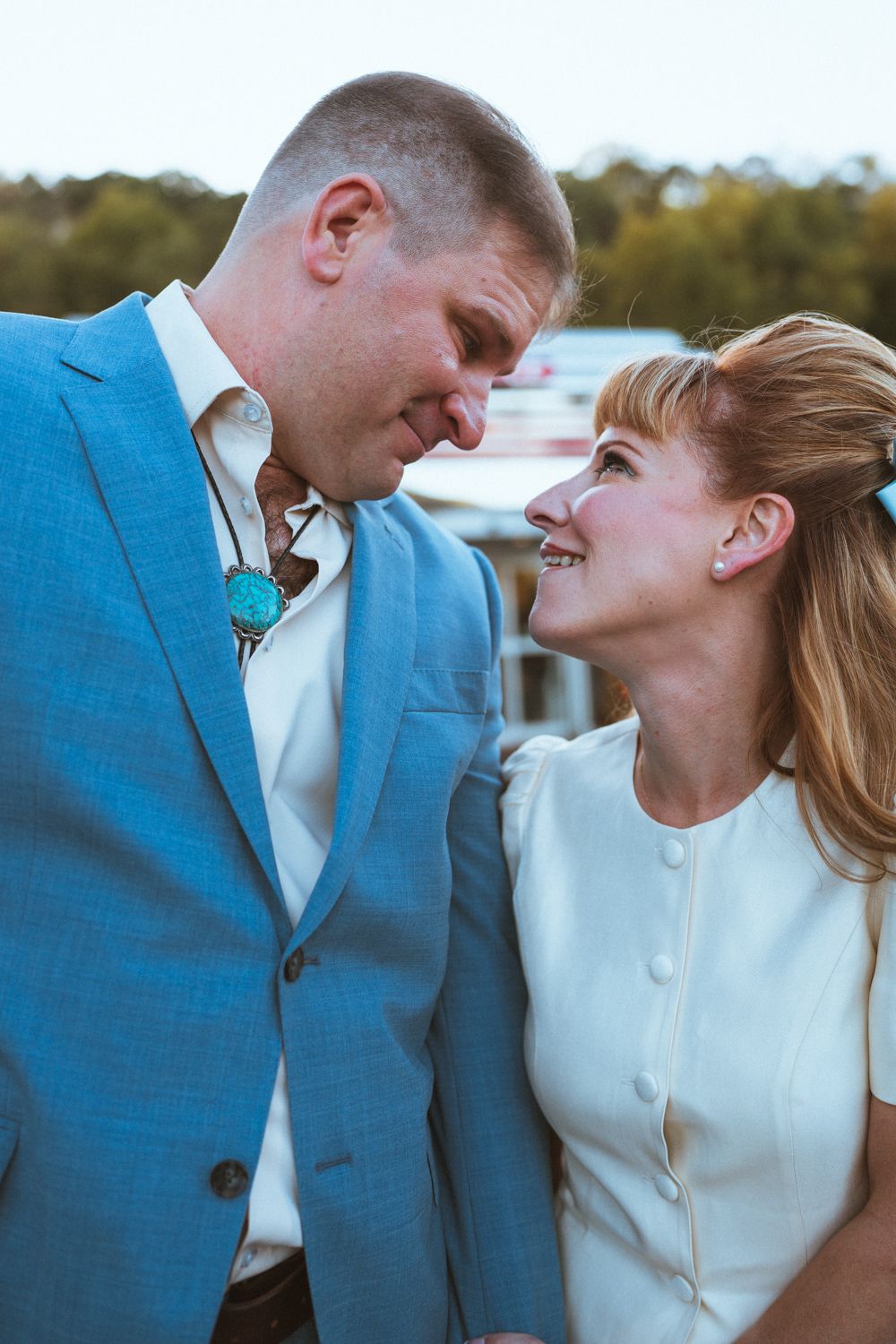 Romantic couple shares intimate moment near classic car at vintage diner setting.
