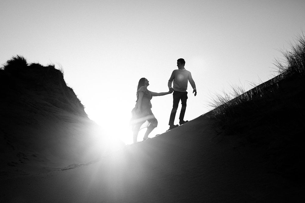 Silhouettes of people walking along a hillside ridge at sunset.