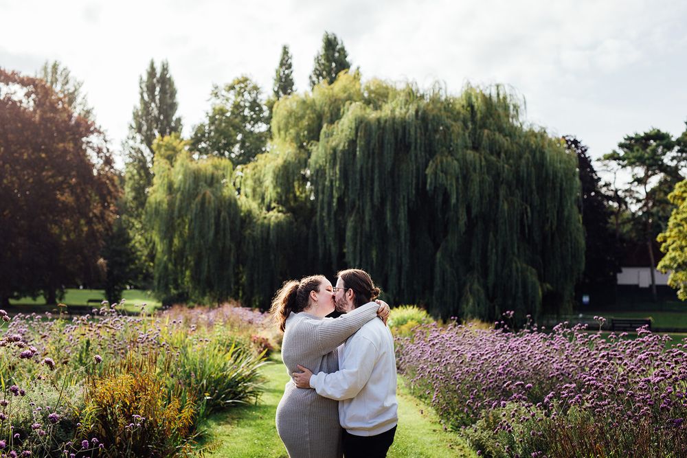 Romantic moment under a weeping willow tree surrounded by vibrant garden flowers.