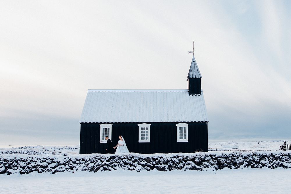Traditional black Icelandic church buildings stand against snowy winter landscape.