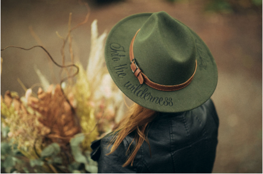Person wearing a green wide-brimmed hat viewed from behind in soft focus.