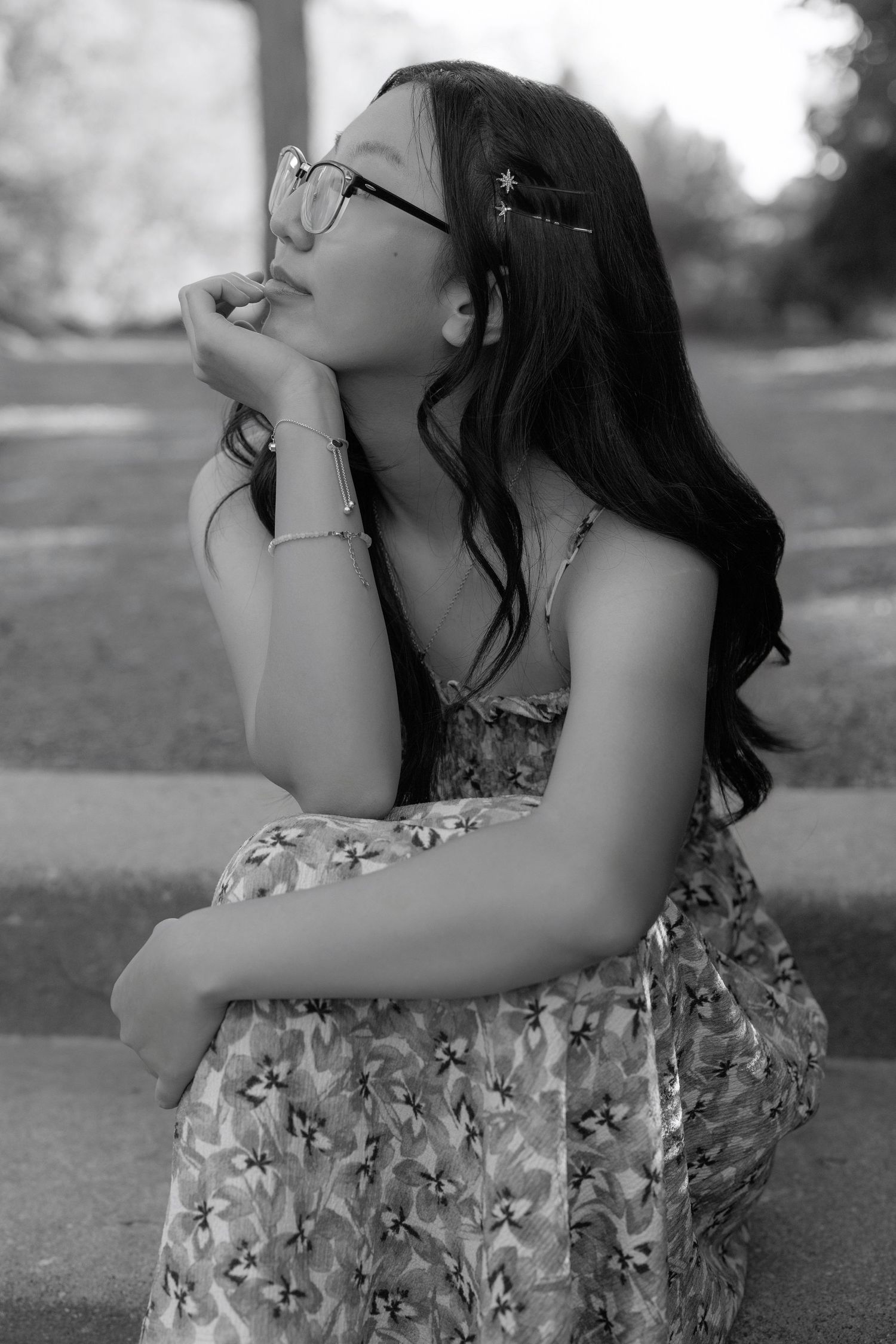 Black and white portrait of person in floral dress with contemplative pose.