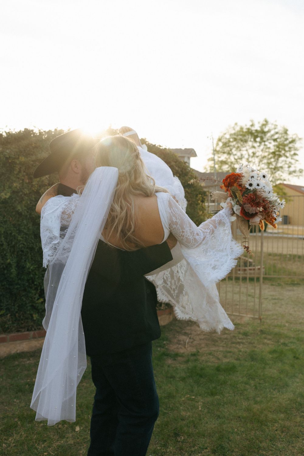 A bride and groom share an intimate moment at sunset in their wedding attire.