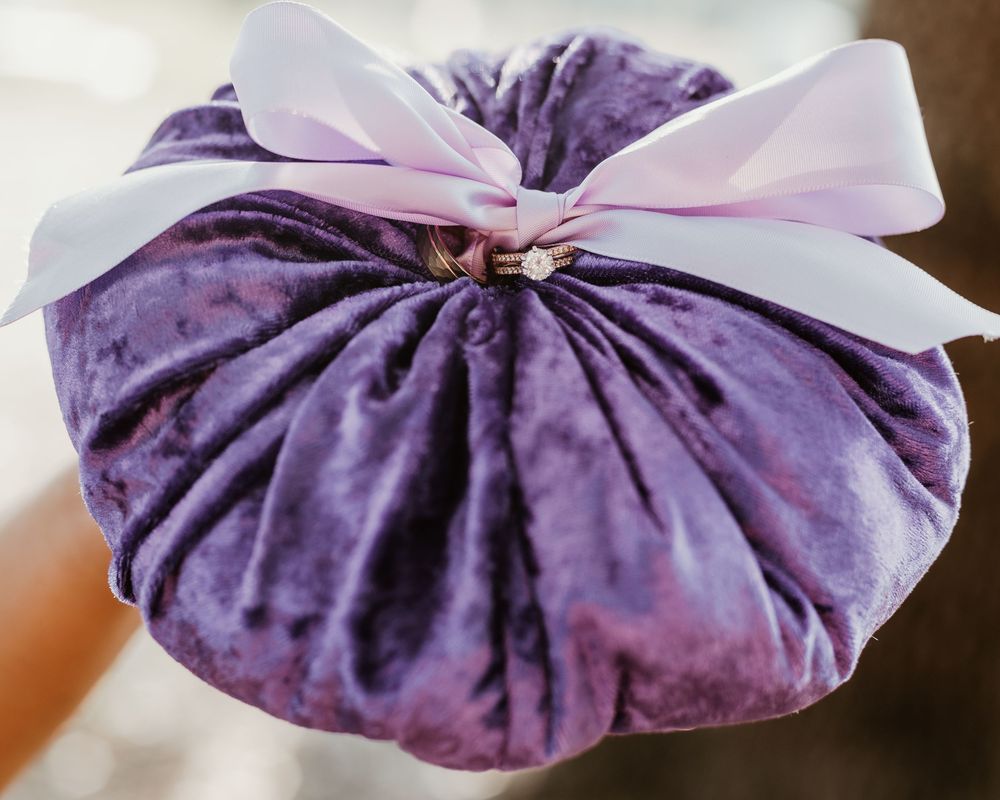 Purple velvet ring bearer pillow with white satin bow detail.