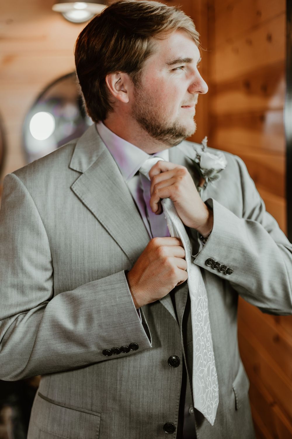Groomsmen adjusting ties and getting ready in rustic wooden room.