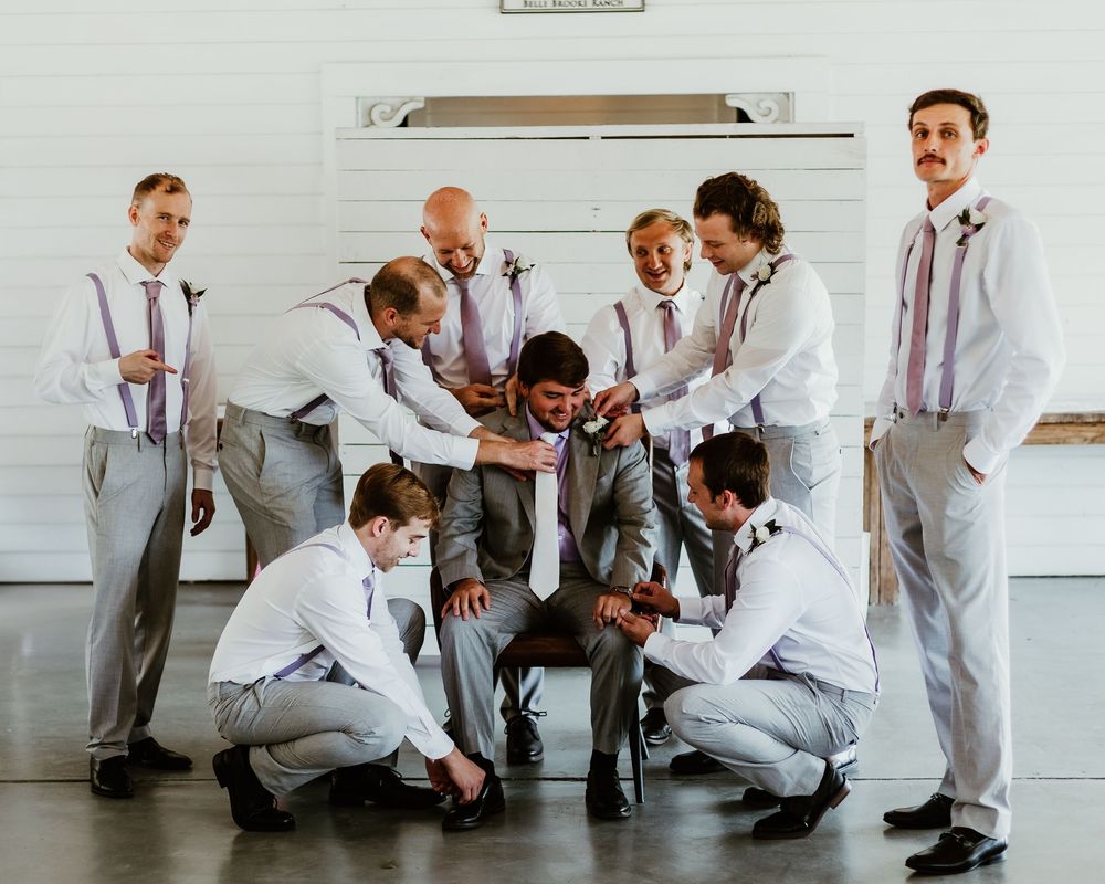 Groomsmen in gray suits playfully posing together before ceremony.