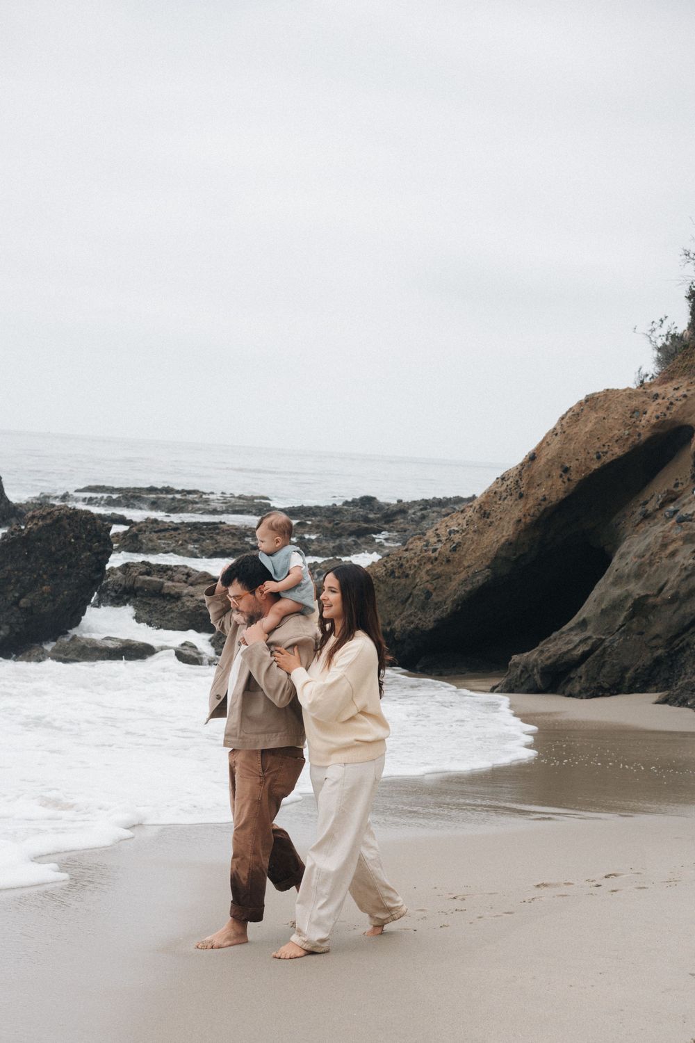 Romantic beach photoshoot sequence with couple dancing together against dramatic coastal rocks and crashing waves.
