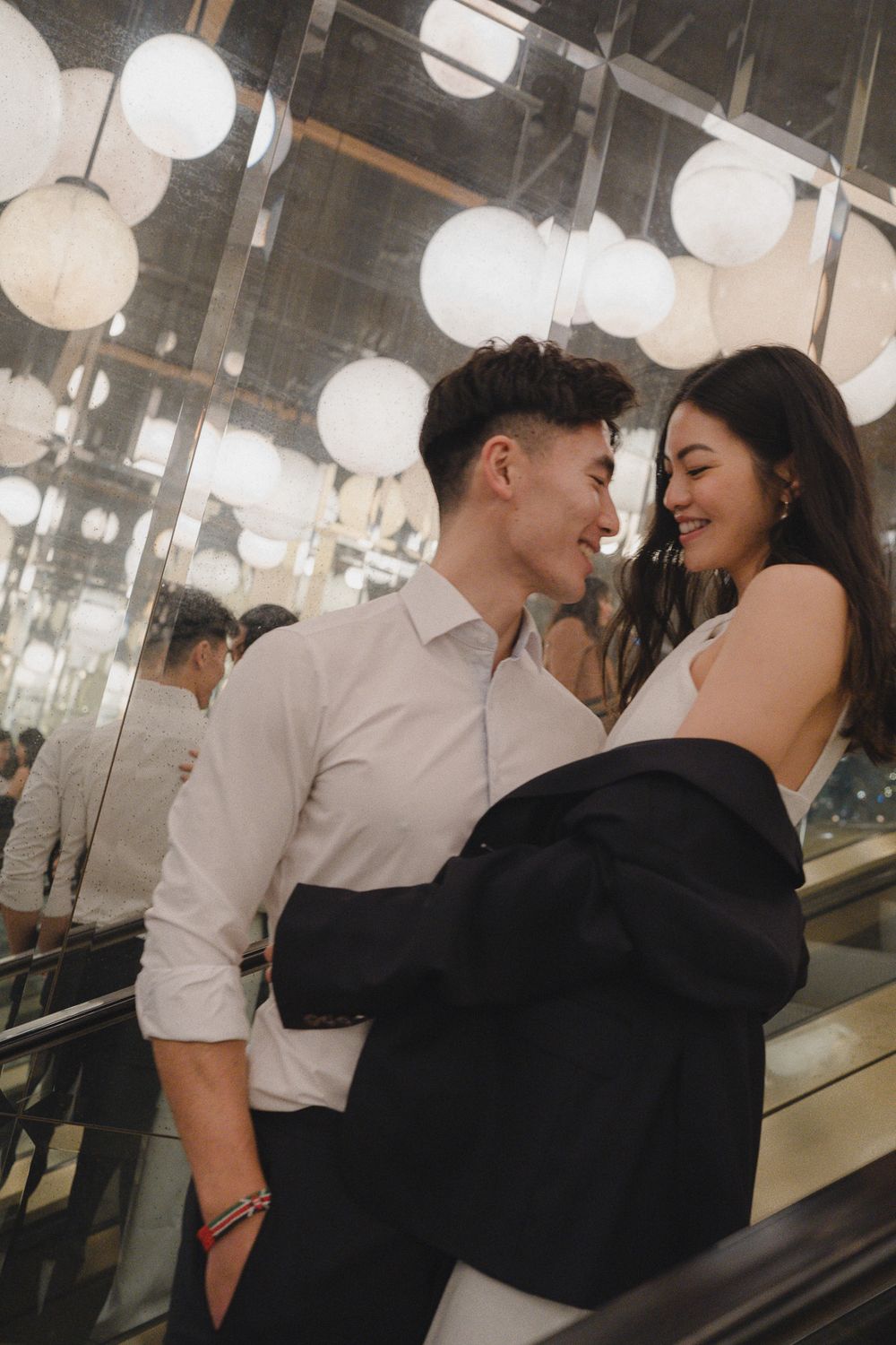 Romantic couple sharing an intimate moment on an escalator surrounded by hanging paper lanterns.
