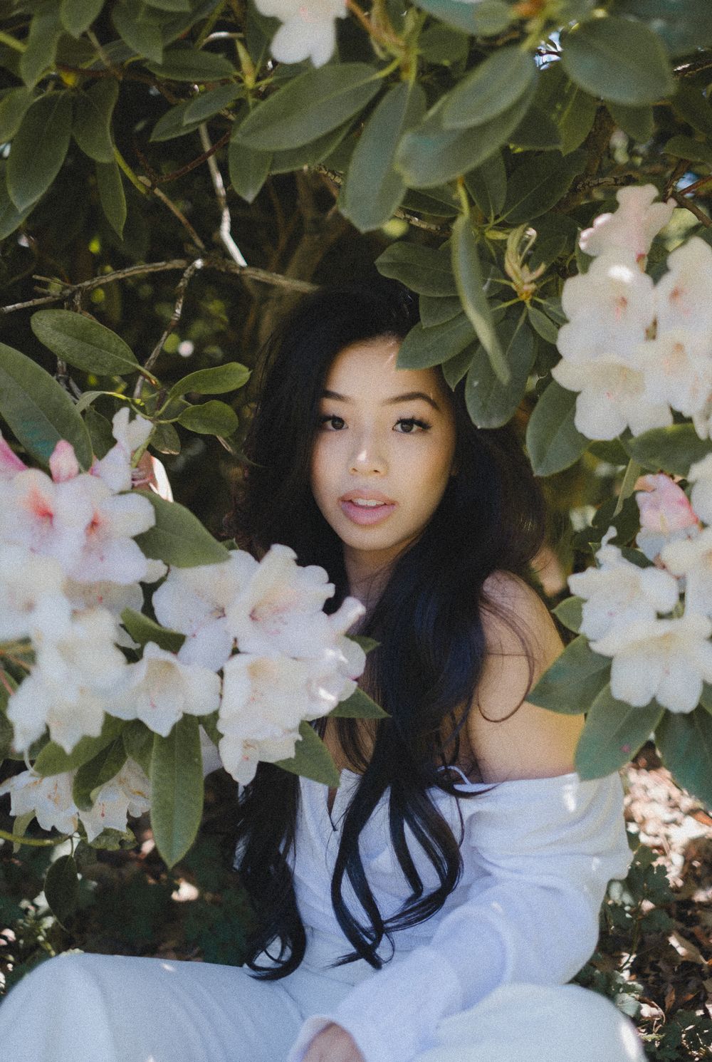 A delicate portrait amidst blooming white flowers and green foliage in a garden setting.