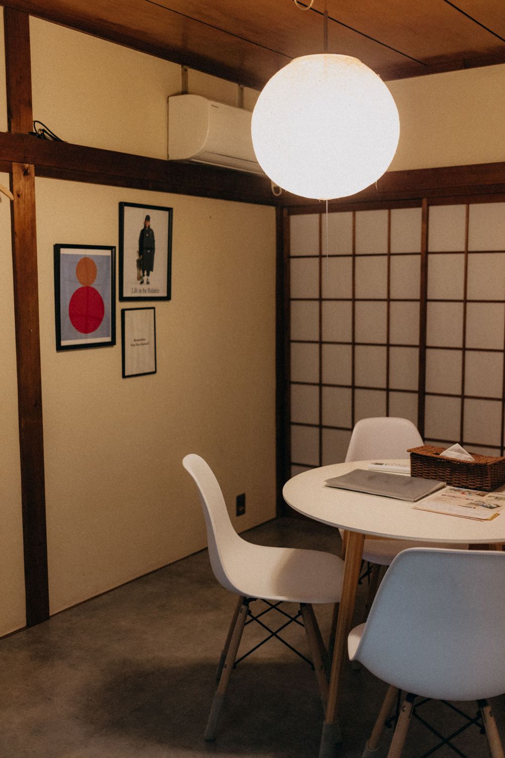 Modern minimalist dining area with round pendant light and traditional Japanese sliding doors.