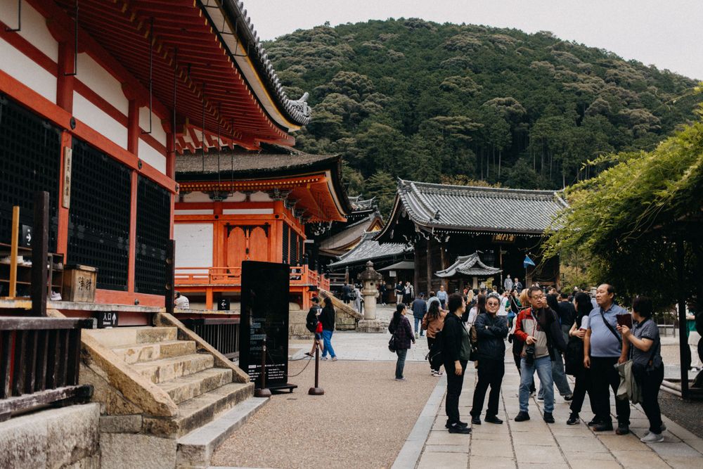 Traditional red temple architecture with tourists walking along the pathway.