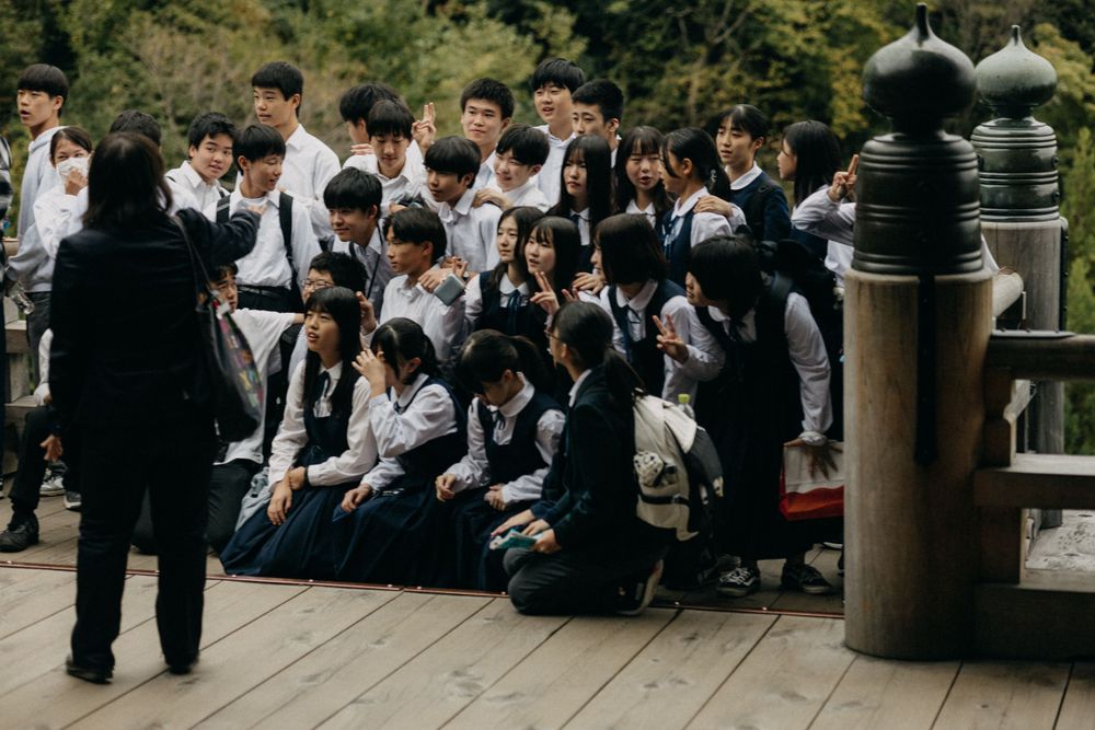 Students in uniforms gather on steps at Kiyomizu-dera temple in Kyoto, Japan.
