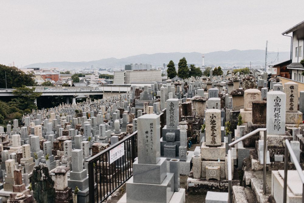 Rows of traditional Japanese gravestones on a hillside overlooking the city.
