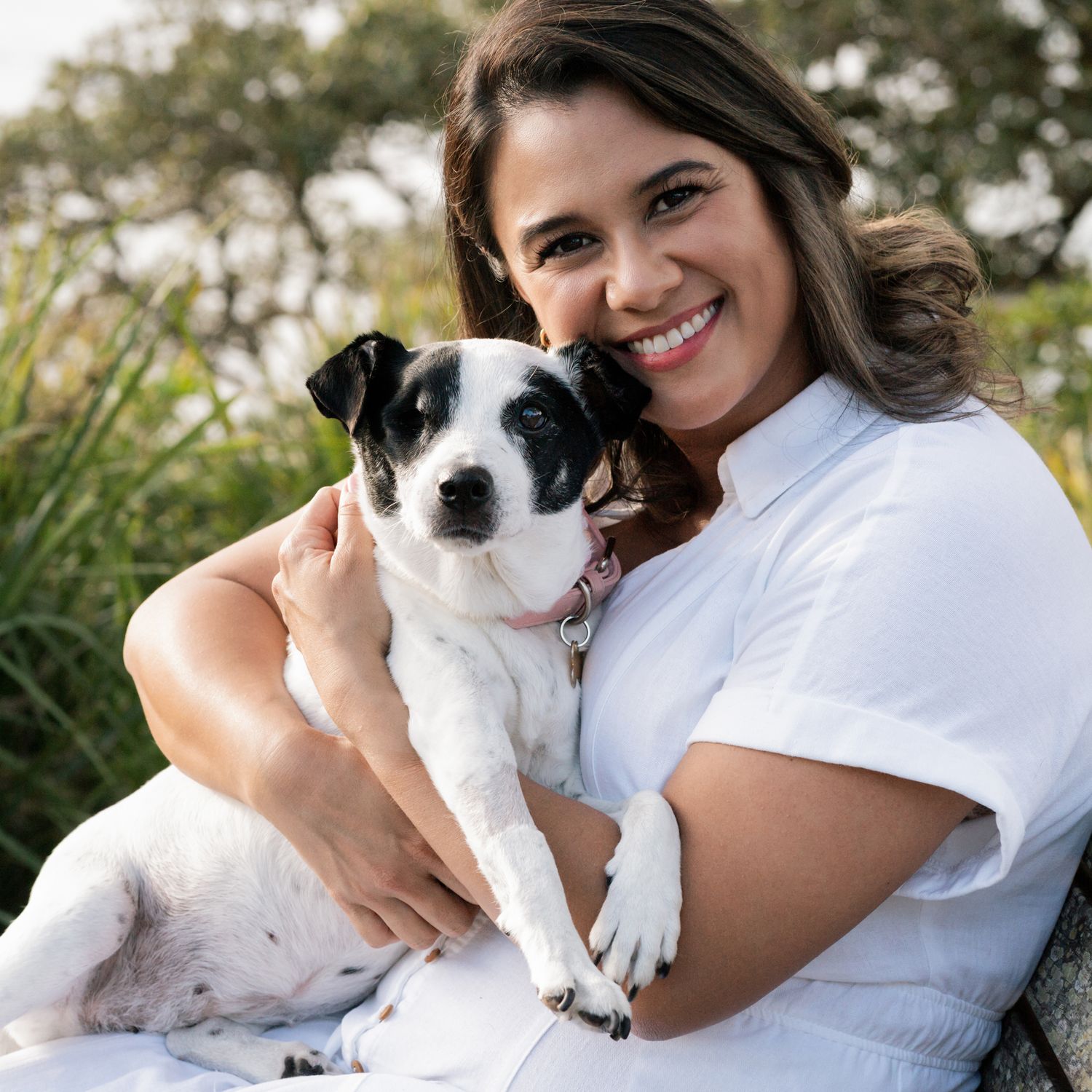 Girl and her small dog smiling and looking towards the camera during a professional pet friendly photoshoot in Sydney Lilli Pilli Reserve