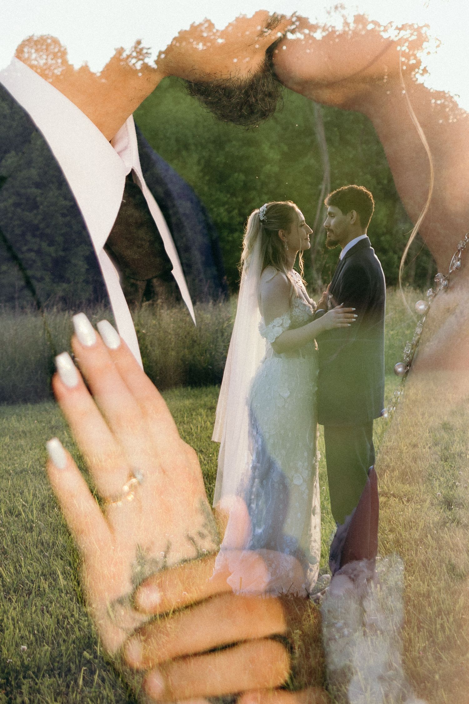 Hands with wedding rings are raised against a sunlit outdoor background. NC Editorial wedding photographer for historic venue