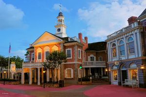 Historic brick courthouse with white clock tower and portico illuminated at dusk in colonial American town square.