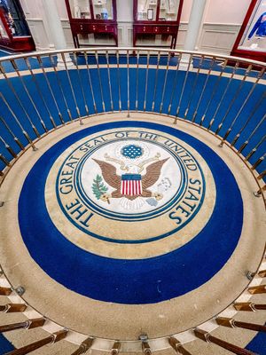 The Great Seal of the United States embedded in a blue and beige circular floor design at a government building.