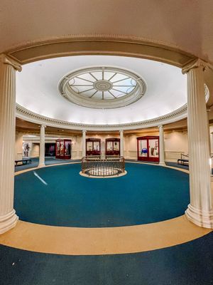 Panoramic view of a grand circular rotunda with white columns and a decorative domed ceiling with skylight.