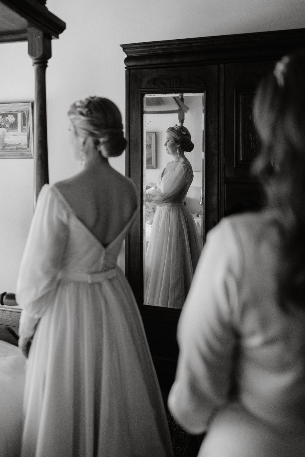Elegant black and white reflection of a bride in a classic white wedding dress with long sleeves and open back.