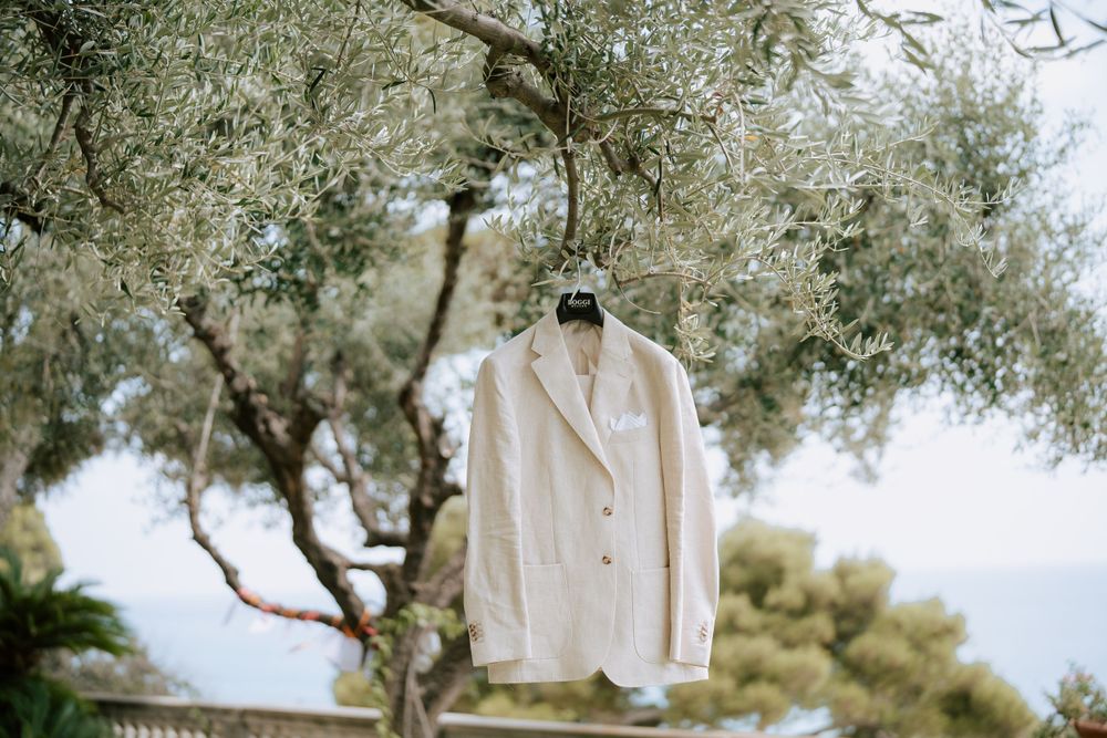 l'abito dello sposo fotografato appeso ad un albero a villa casa rossa ad imperia, come sfondo oltre al verde la vista mare.