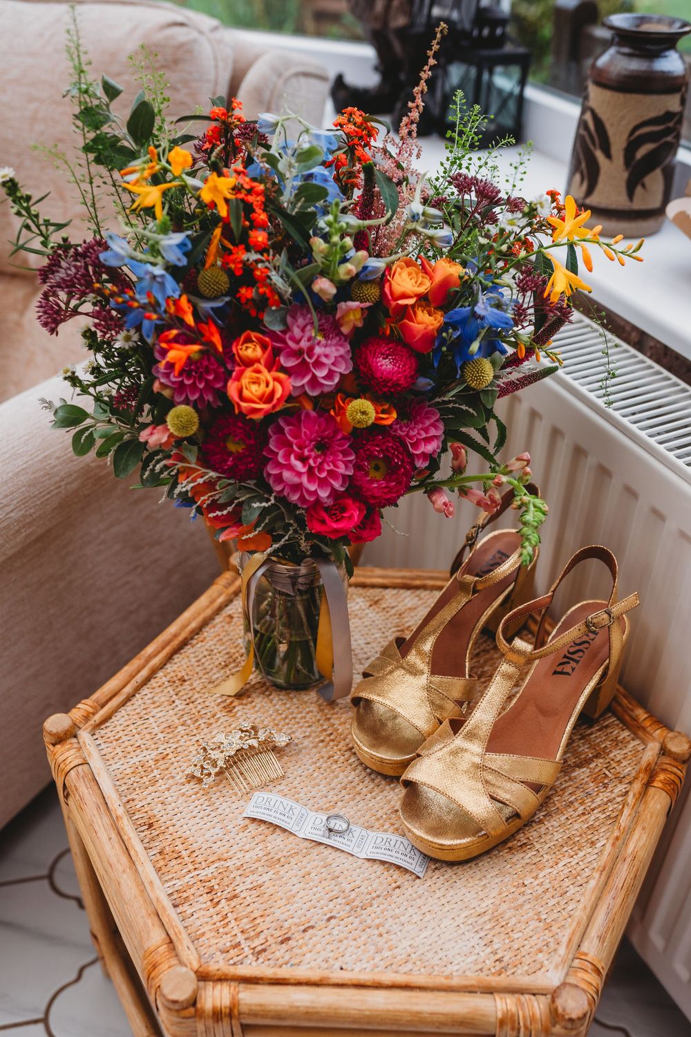 Vibrant floral arrangement with orange and pink blooms sits atop a rustic wooden table with macrame decor.