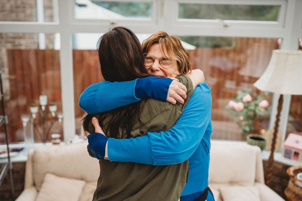 Emotional embraces shared between wedding guests in a bright indoor setting.