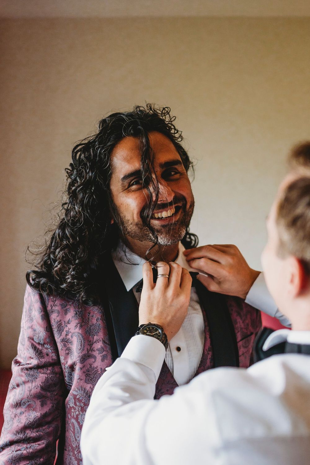 Getting ready moment before wedding with burgundy velvet jacket.