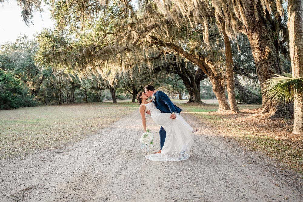 Wedding couple sharing romantic moment on tree-lined dirt path.