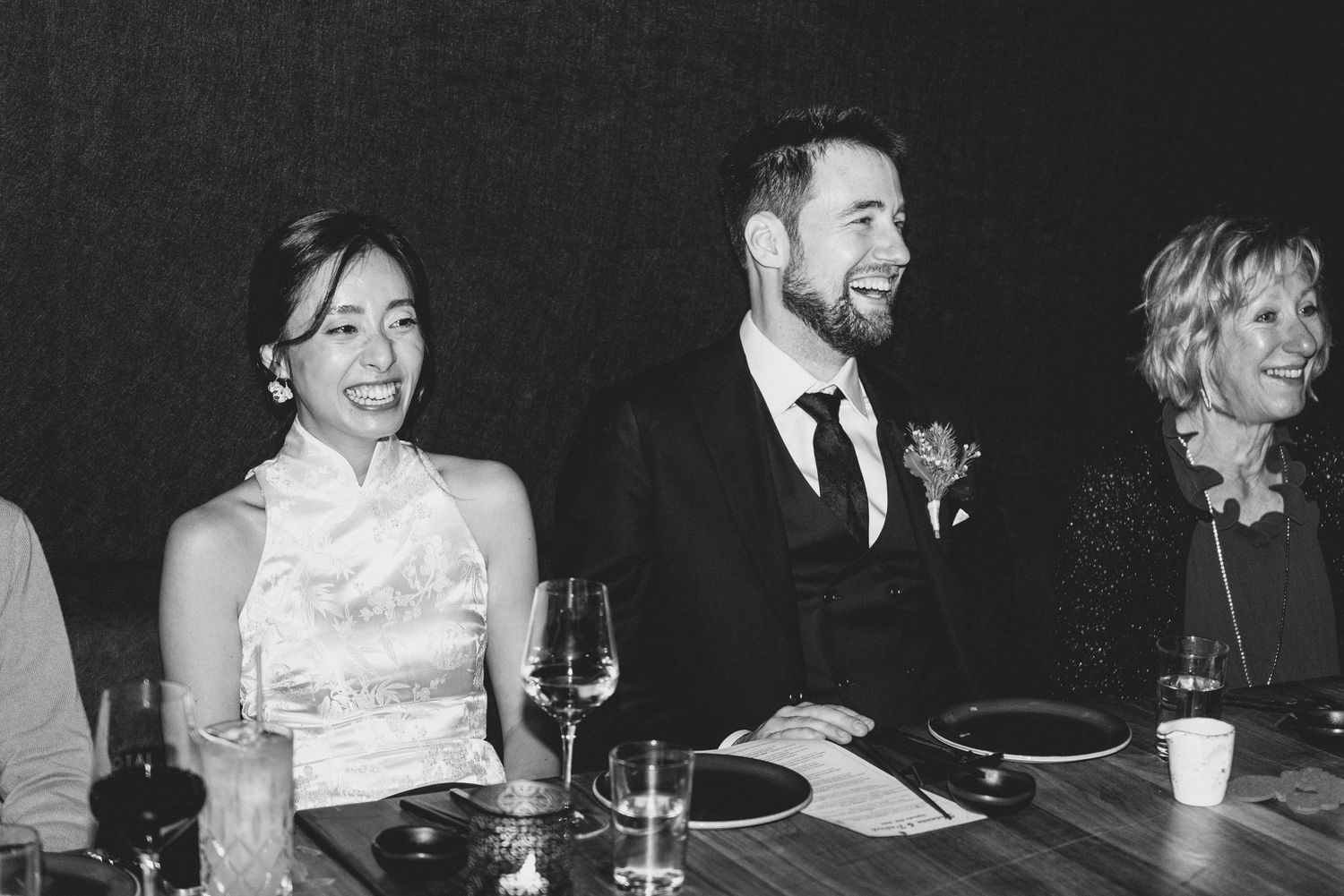 Group of people laughing and enjoying conversation during an elegant dinner party gathering.