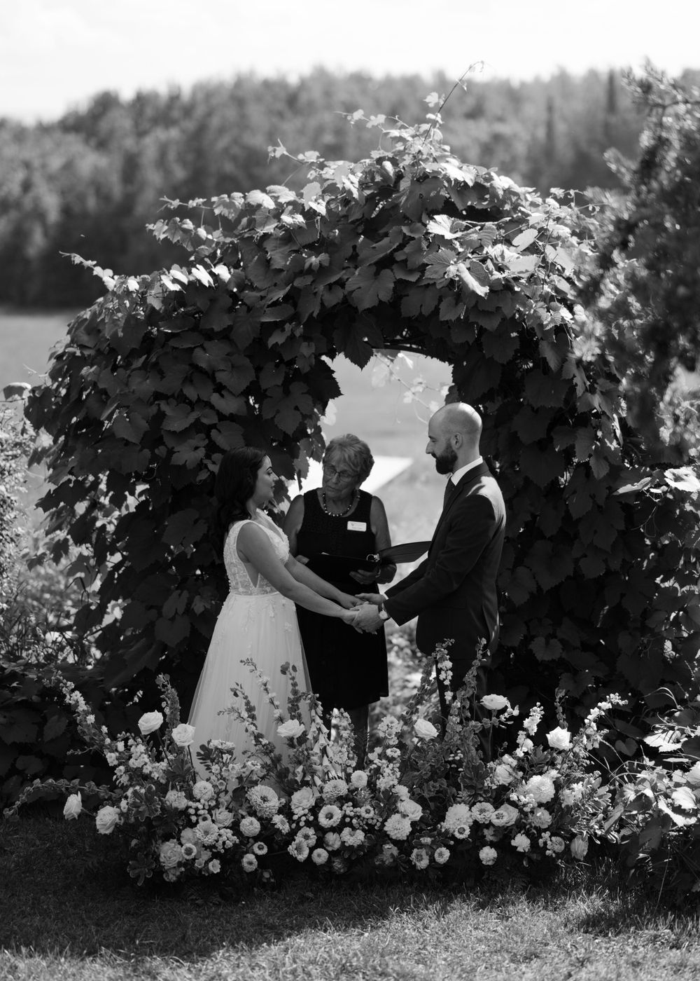 A couple shares intimate moments among flowering garden vines and bushes.