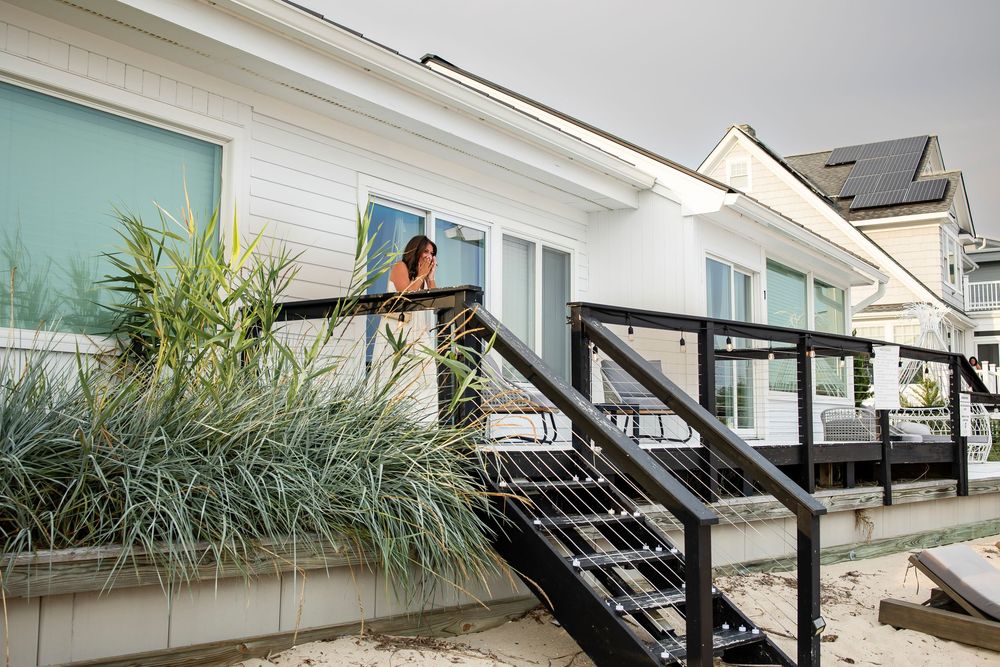 Modern glass-enclosed balcony with black metal railings and decorative plants creates an elegant outdoor living space.